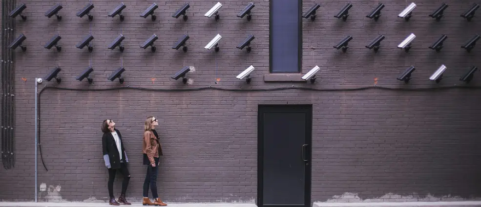 Two people standing in front of a wall of security cameras